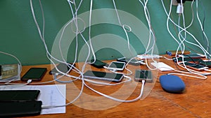 Many smartphones and mobile phones charging on the table