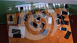 Many Smartphones and Mobile Phones Charging on the Table