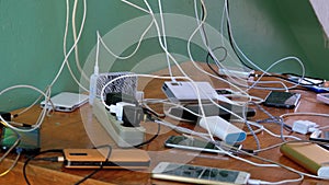 Many Smartphones and Mobile Phones Charging on the Table