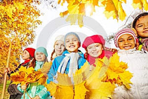 Many smiling kids with rake and yellow leaves