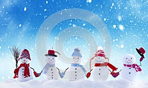 Many snowmen standing in winter Christmas landscape.