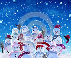 Many snowmen standing in winter Christmas landscape.