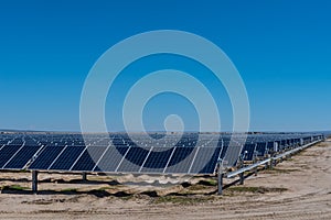 Many solar panels in the desert with blue sky