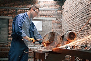 Many of the sparks. Welding the metal. Factory worker in blue uniform is indoors