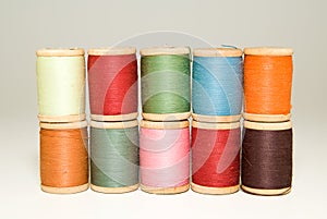 Many spools of thread of different colors on a white