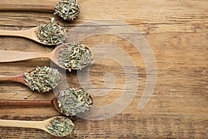 Many spoons with aromatic dried lemongrass on wooden table, flat lay. Space for text