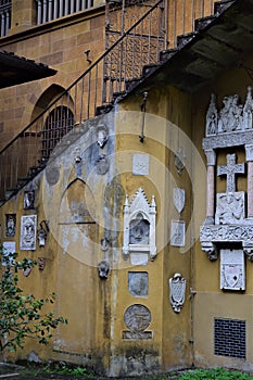 Many stone coats of arms on the wall, located under the staircase, overlooking the park, of the Villa Stibbert in Florence.