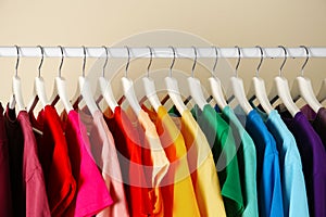 Many t-shirts hanging in order of rainbow colors