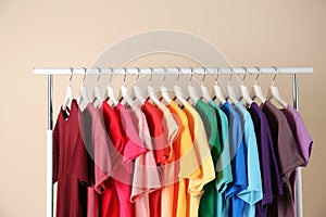 Many t-shirts hanging in order of rainbow colors