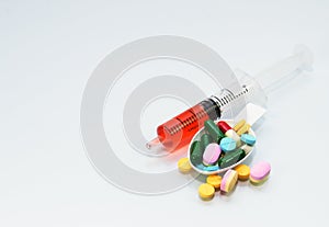 Many tablets and pill on spoon and liquid drug in syringe