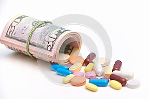 Many tablets or pills lie near rolled up dollars, symbolize paid expensive medicine and corruption, isolated over white background