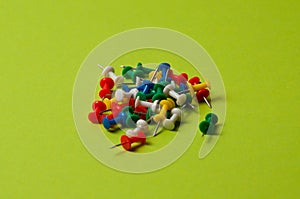 Many thumbtacks of different colors on green designer paper