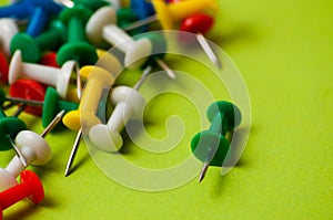 Many thumbtacks of different colors on green designer paper