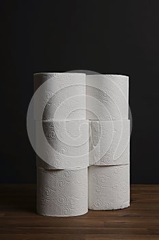 Many toilet paper rolls piled in a heap. Soft hygienic paper. Wooden table on black background