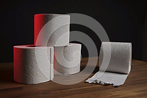 Many toilet paper rolls piled in a heap. Soft hygienic paper. Wooden table on black background