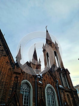 Many towers, weathervanes and stained glass windows of an old brick catholic church, side view