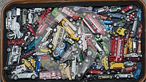 Many toy cars.  Photo of multi-colored toy cars in an old suitcase