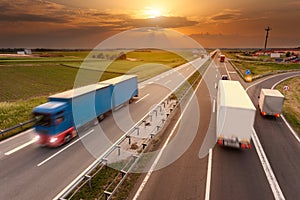 Many trucks in motion blur on the highway at sunset