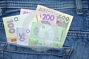 Many Ukrainian money bills of various denominations and colors UAH  hryvnia  in the back pocket of blue jeans.