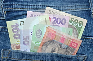 Many Ukrainian money bills of various denominations and colors UAH  hryvnia  in the back pocket of blue jeans.