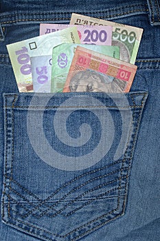 Many Ukrainian money bills of various denominations and colors UAH  hryvnia  in the back pocket of blue jeans.