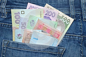 Many Ukrainian money bills of various denominations and colors UAH  hryvnia  in the back pocket of blue jeans.