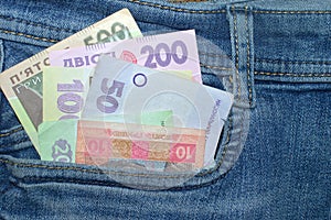 Many Ukrainian money bills of various denominations and colors UAH  hryvnia  in the front pocket of blue jeans.