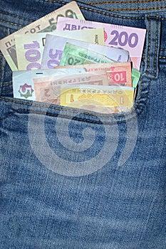 Many Ukrainian money bills of various denominations and colors UAH  hryvnia  in the front pocket of blue jeans.