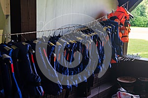 Many used blue and orange life jackets hanging in building
