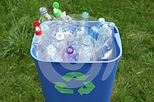 Many used bottles in trash bin outdoors. Plastic recycling