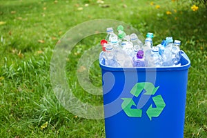 Many used bottles in trash bin outdoors, space for text.