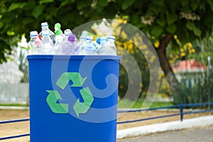 Used bottles in trash bin outdoors, space for text. Plastic recycling