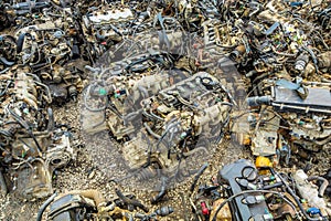 many used internal combustion engines on the ground of junkyard at cloudy day