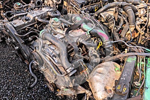 many used internal combustion engines on the ground of junkyard at cloudy day