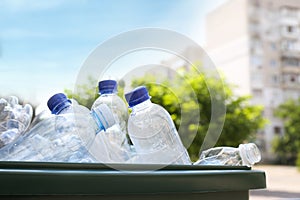 Many used plastic bottles in trash bin outdoors, closeup. Recycling problem