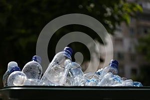 Many used plastic bottles in trash bin outdoors, closeup. Recycling problem