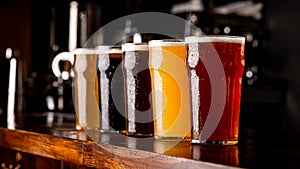 Many varieties of craft beer. Misted glass goblets with ale, lager, and unfiltered drink on bar