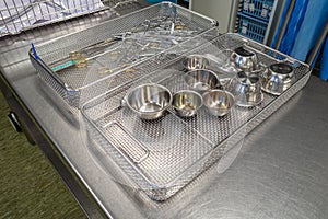 Many various cleaned and disinfected surgical instruments lie unsorted in metal sieves