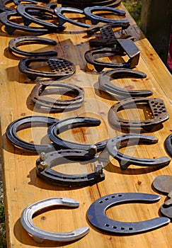 Many various horseshoes on a wooden table