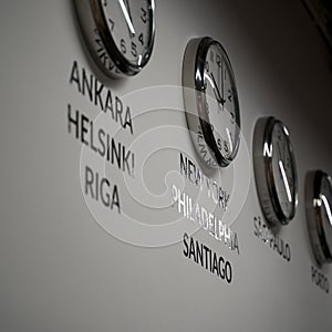 Many wall clocks on the white wall of business office showing time of different cities of the world