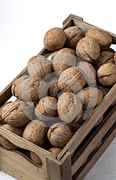 Many walnuts in a mini wooden crate on a white background on top view Still life photography
