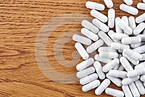 Many white capsules on wooden background. Pills and medicine