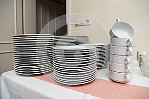 Many white ceramic clean modern dishes on a table