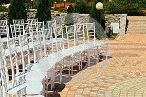 Many white chairs lined up for guests of a wedding celebration in nature.