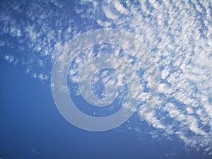 Many white clouds and a moon in sky