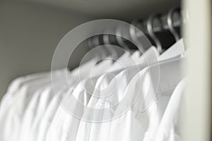 Many white collar clean male shirts hangers cupboard business clothes storage organization closeup