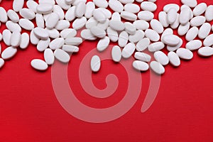 Many white dragee candies on red background, flat lay. Space for text