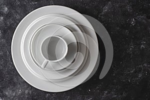 Many white empty plate and cup on black background, close up