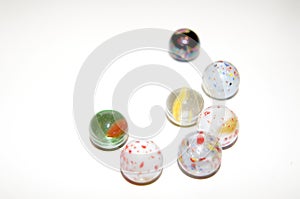 Many white marbles with two glas marbles and one steel marble