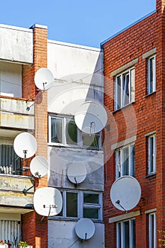 Many white parabolic satellite antenna dishes hanged on wall of suburban perfab block of flats